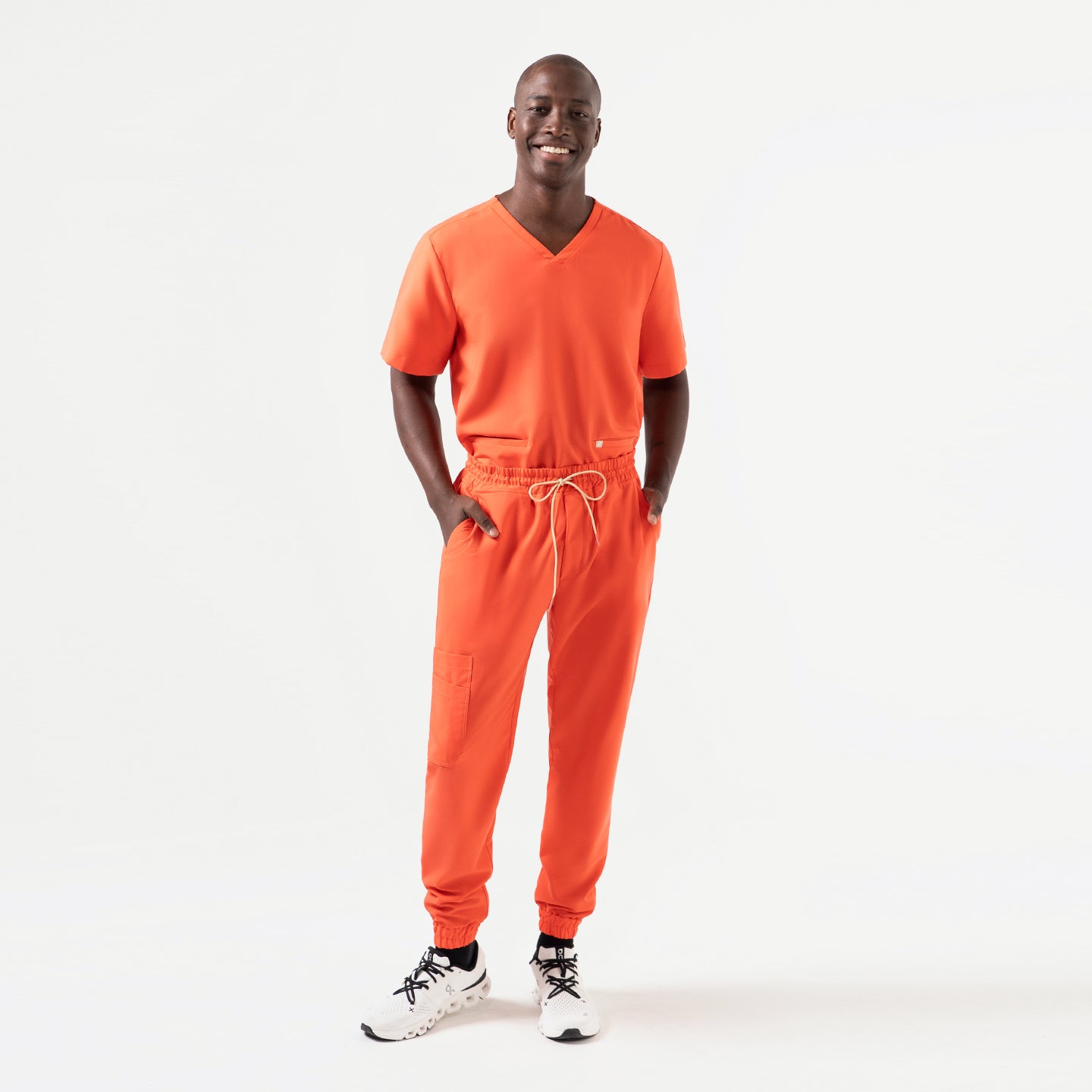 Designed for all-day performance, the Tiger-Orange double-pocket scrub top is worn by the model in a full matching set, featuring durable fabric, easy mobility, and functional details that blend practicality with a standout color.
