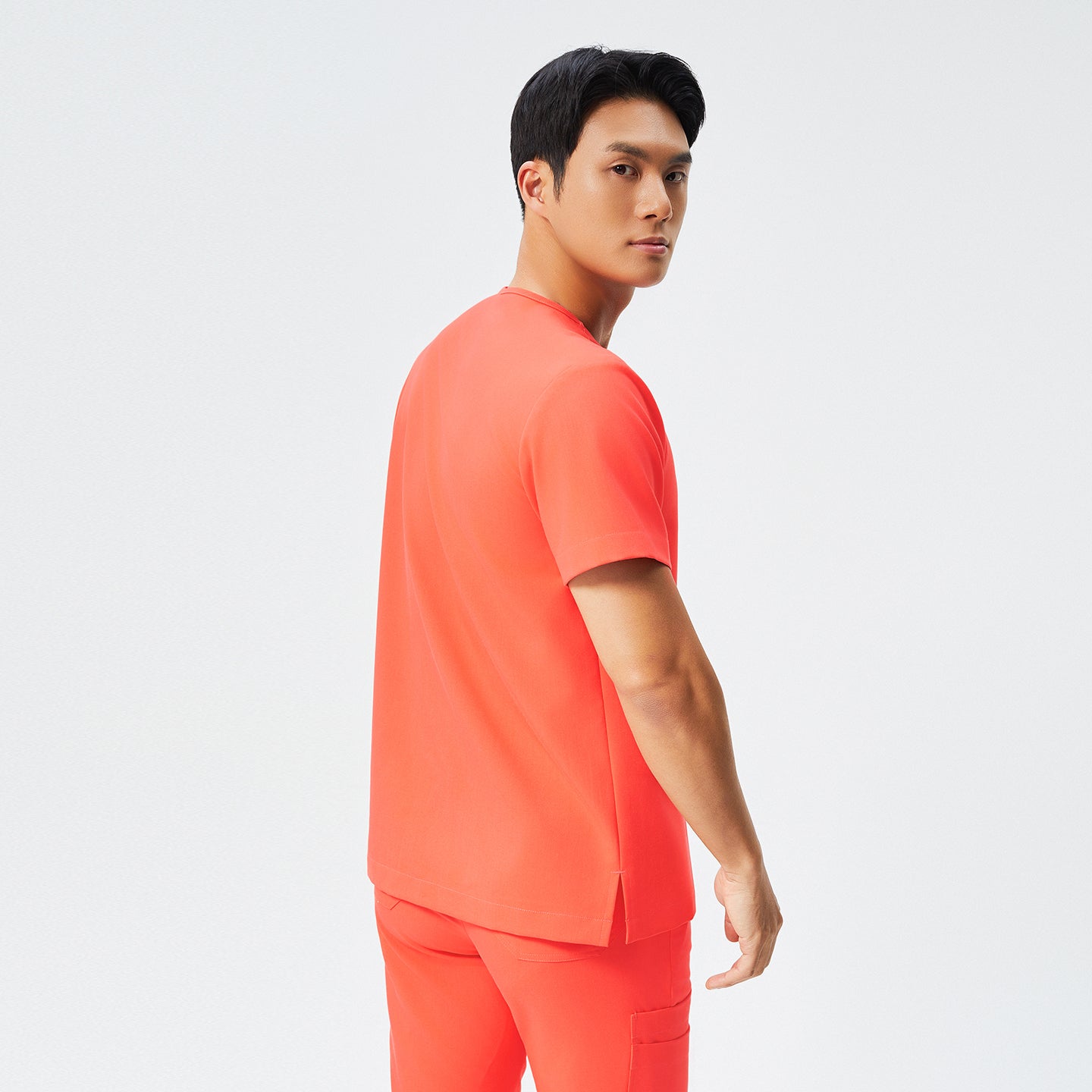 Image of Man wearing tiger orange scrubs with short sleeves and matching pants, facing away,Tiger Orange