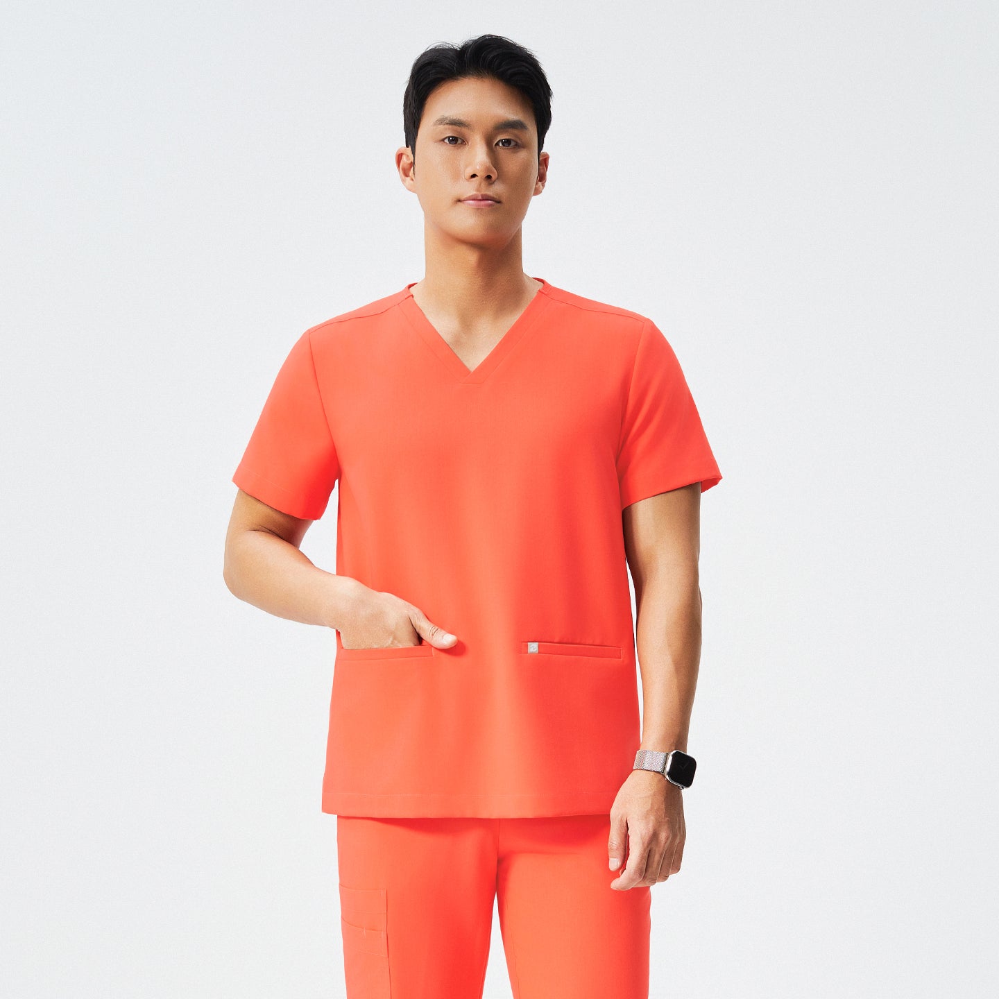 Image of Man wearing tiger orange scrubs with a V-neck and double pockets, accessorized with a black stethoscope,Tiger Orange