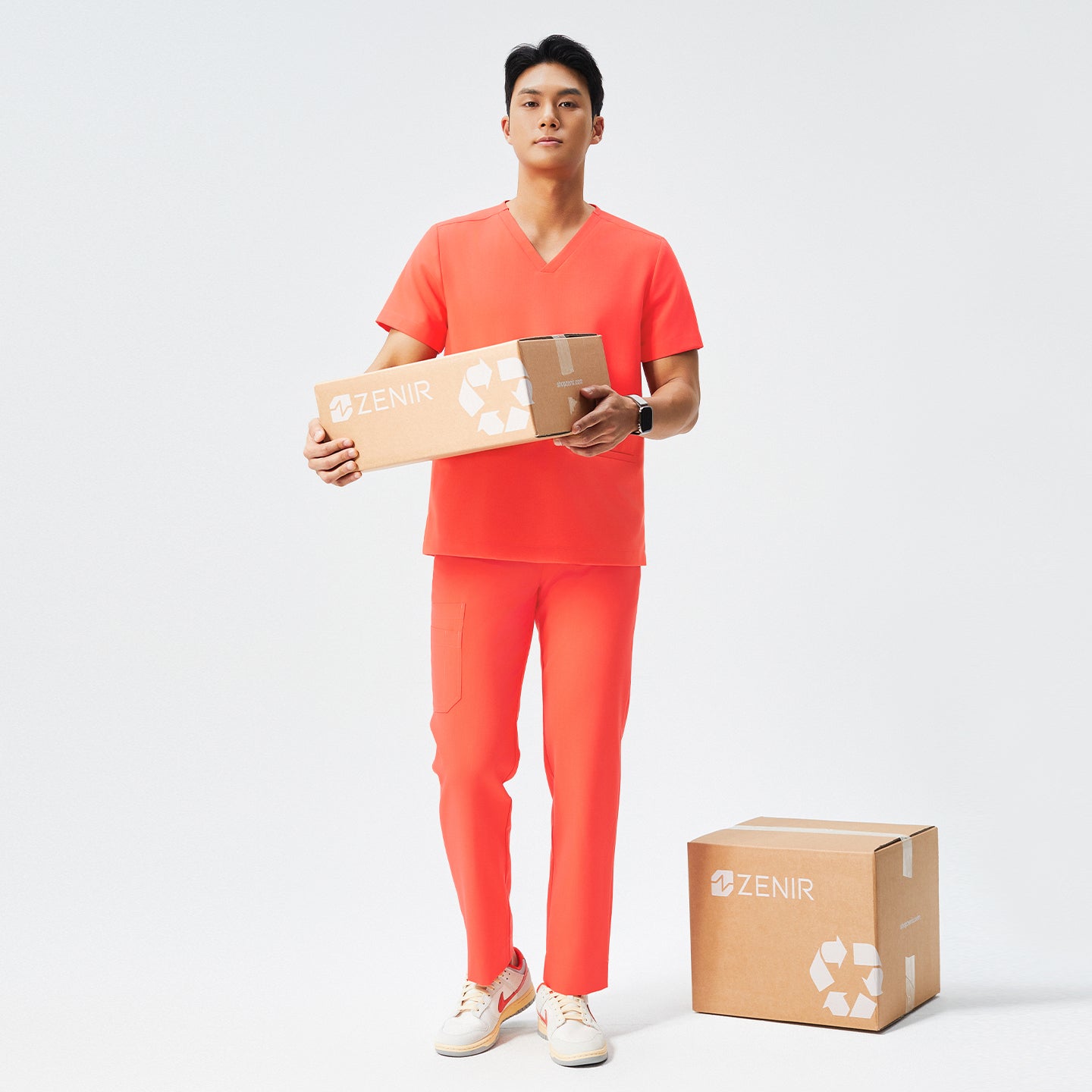 Image of Man wearing tiger orange scrubs with a V-neck and double pockets, paired with white sneakers,Tiger Orange