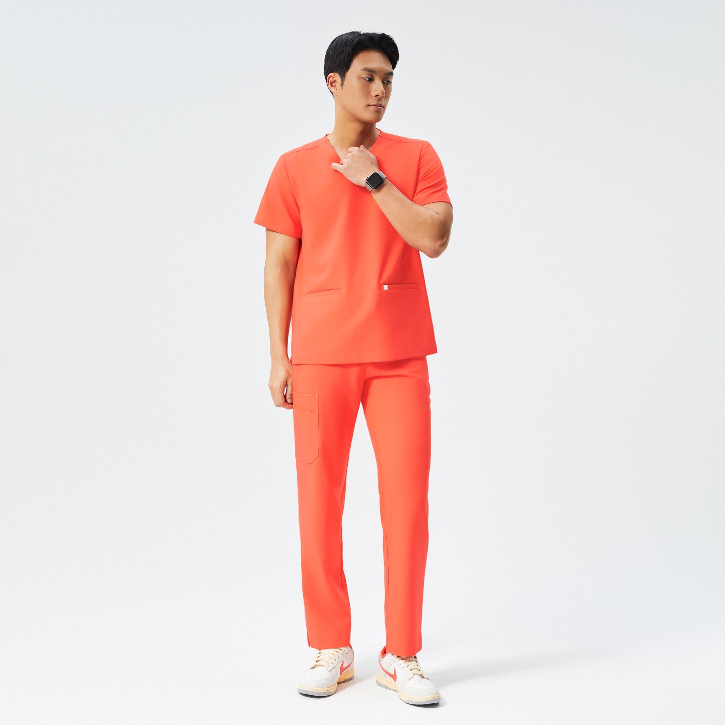 Image of Man wearing tiger orange scrubs with a V-neck top and jogger-style pants, paired with white sneakers,Tiger Orange