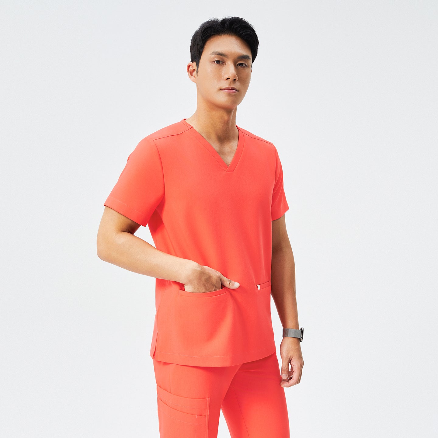 Man in tiger orange scrubs with a V-neck and double pockets, holding a black stethoscope around his neck,Tiger Orange