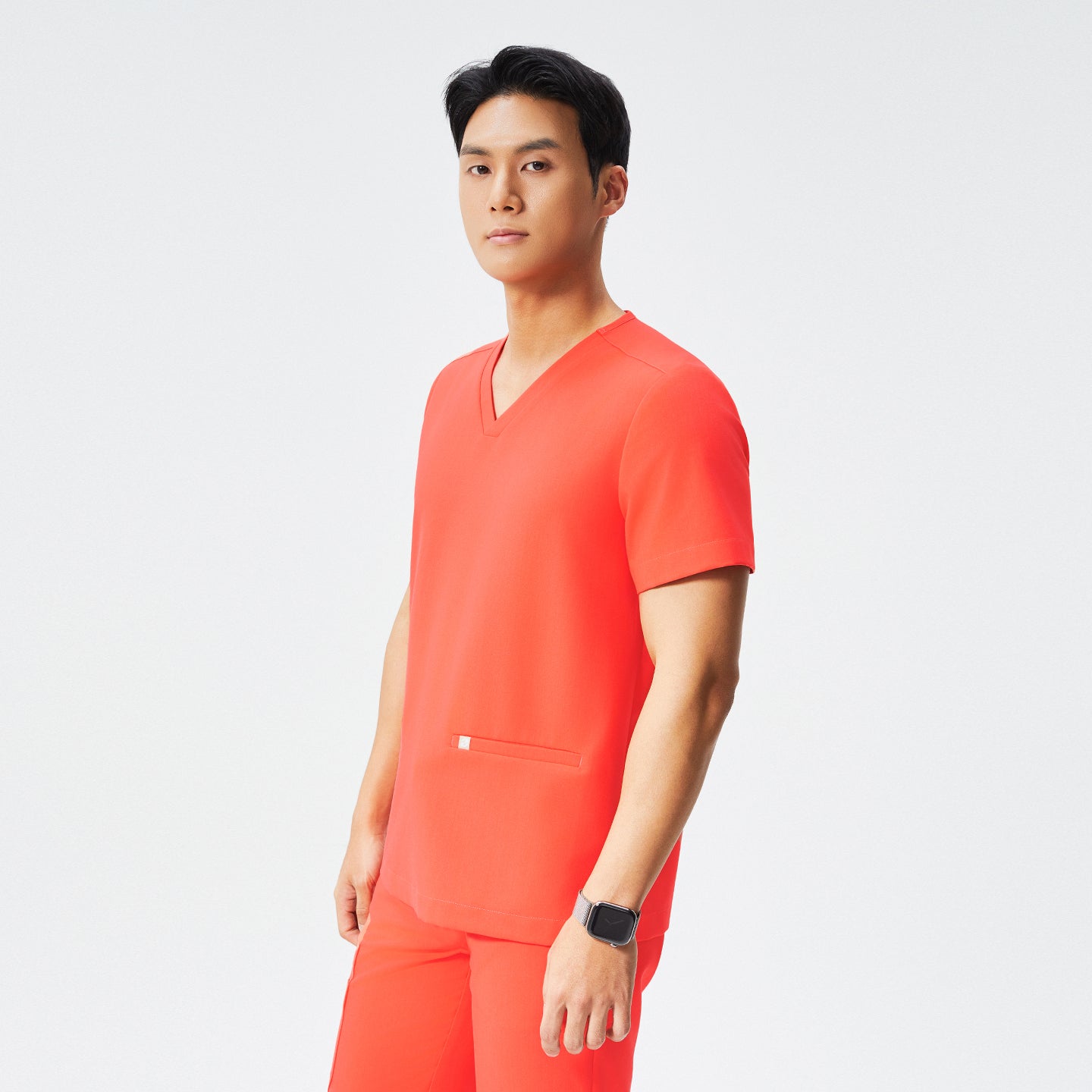 Image of Man wearing a tiger orange scrub set with a double-pocket V-neck top, tiger orange