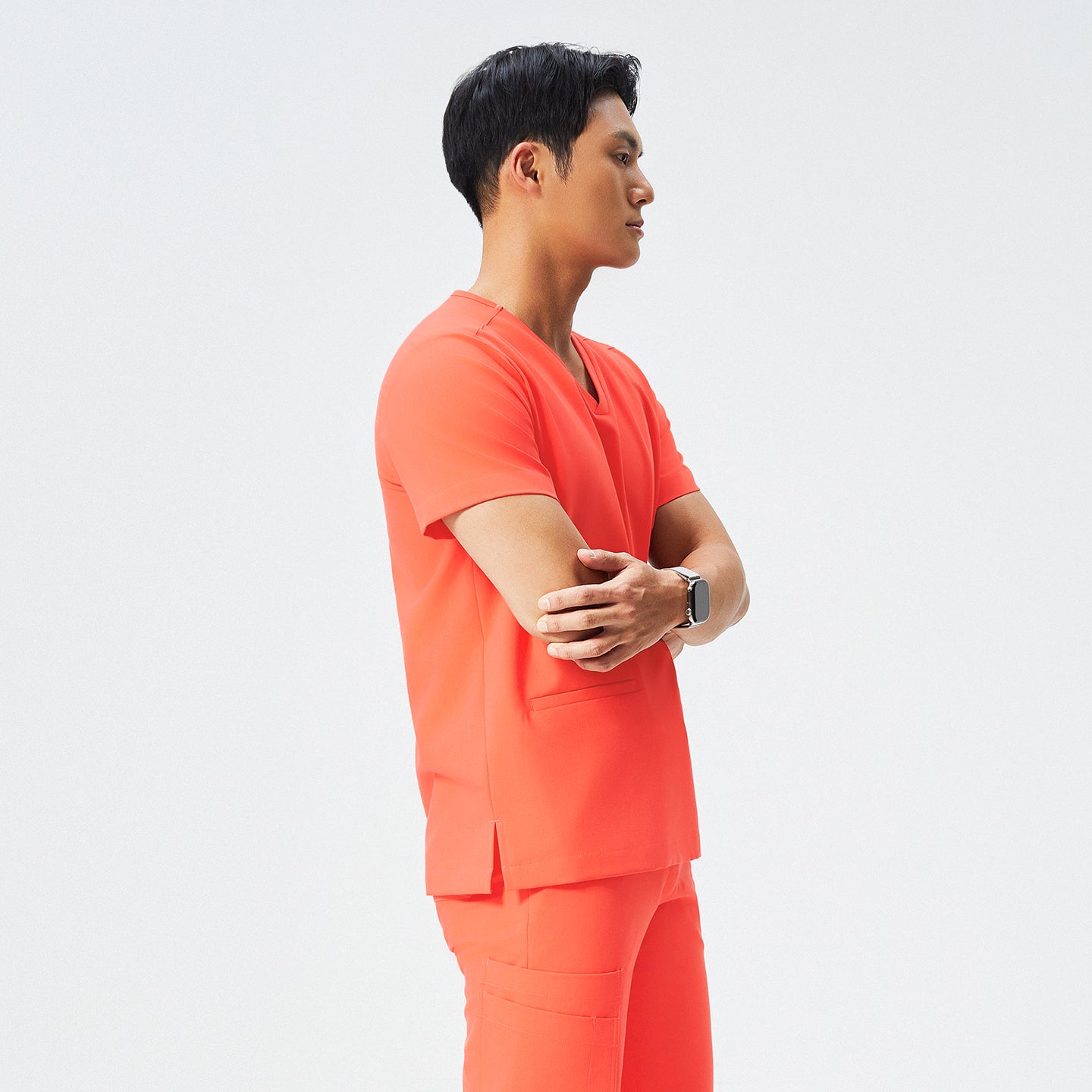 Image of Man wearing tiger orange scrubs with a V-neck and double pockets, looking to the side,Tiger Orange