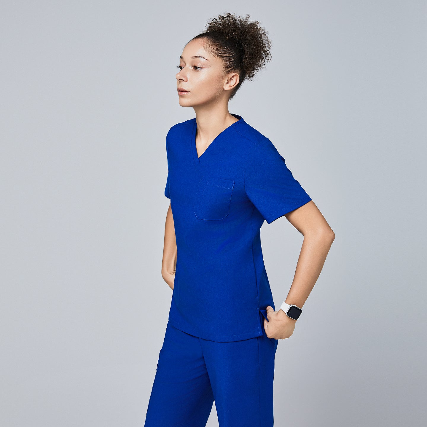 Side profile of a model wearing Zenir royal blue 3-pocket scrub top and matching pants,Royal Blue