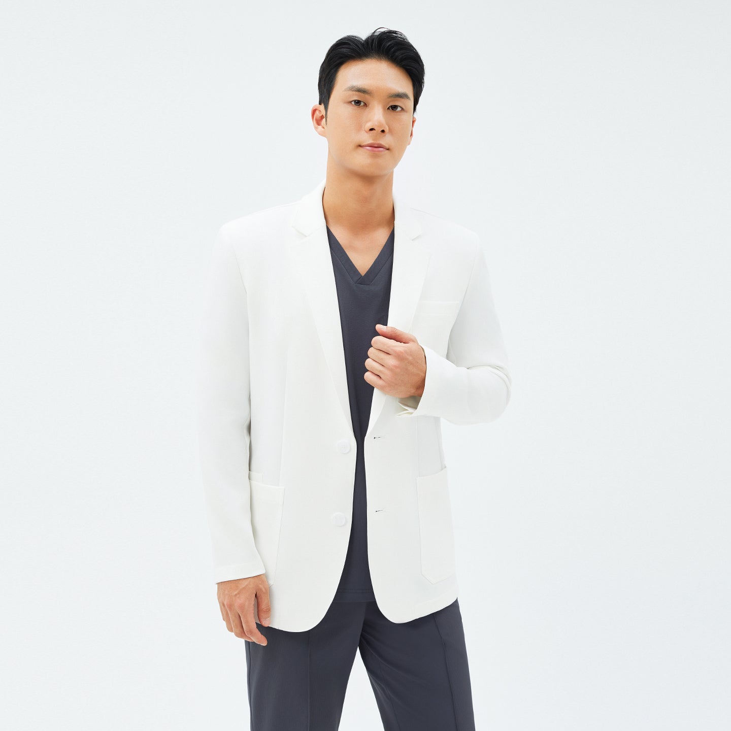 Male model adjusting the front of the TUL LCM-12 Men’s Short Lab Coat in White Ivory, revealing its two-button closure.