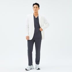 Image of Full-body shot of a male model wearing the TUL LCM-12 Men’s Short Lab Coat in White Ivory over a dark V-neck scrub top and matching pants.