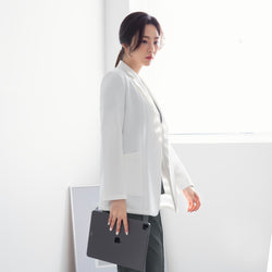 Image of Side profile of a model in TUL LCW-01 Women’s Short Lab Coat, holding a tablet. Light from a nearby window illuminates the coat’s smooth fabric and tailored sleeve design.