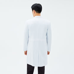 Image of Back view of TUL LCM-11 Men’s Long Lab Coat in White, highlighting the structured waist seam and straight hem. The model’s black scrub pants are visible below the coat.