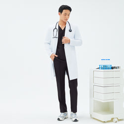 Image of Full-length shot of a male model wearing TUL LCM-11 White long lab coat and matching black scrubs, standing next to a small white medical cart with test tubes.