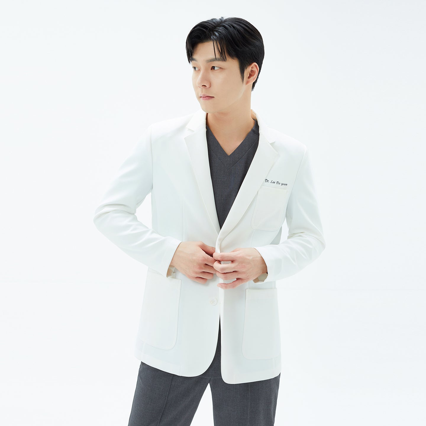 Image of Model fastening the front buttons of the white ivory utility coat, showcasing the large patch pockets.