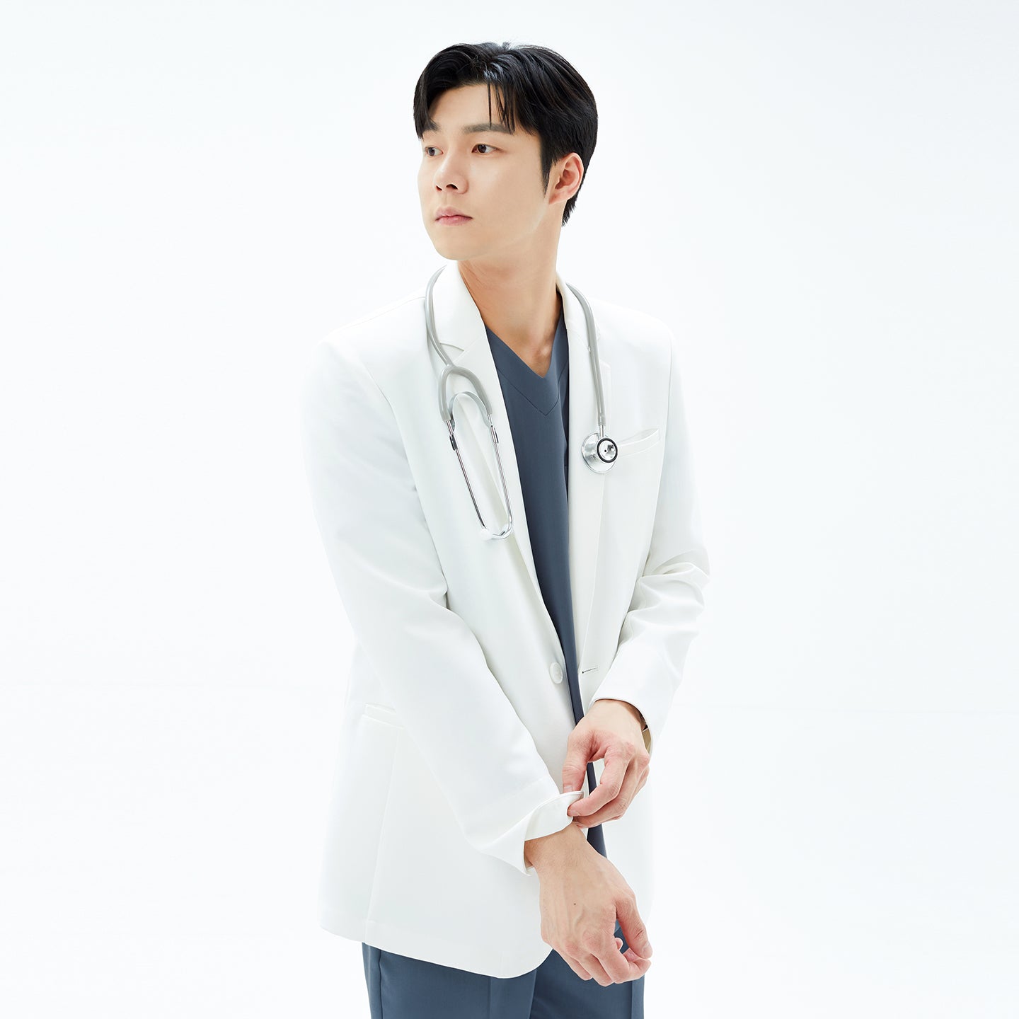 Image of Close-up side angle of the model smoothing the sleeve of the TUL Men’s LCM-17 UltraFit Short Lab Coat — White Ivory.