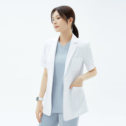 Image of Side profile of the TUL Women’s LCW-15 Lightweight Short Sleeve Lab Coat – White, with the model’s hand in a pocket to illustrate the straight hem.