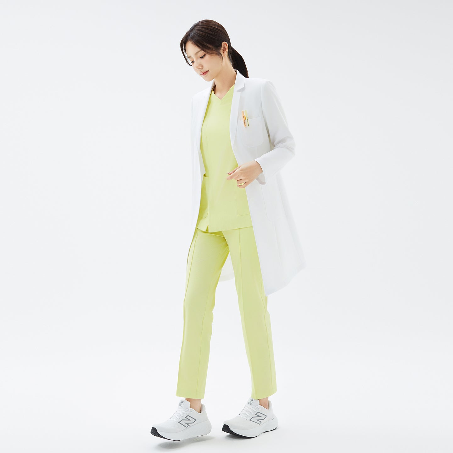 Image of Walking pose with a slight turn, showing the front and side of the TUL LCW-17 Straight Long Lab Coat in White.
