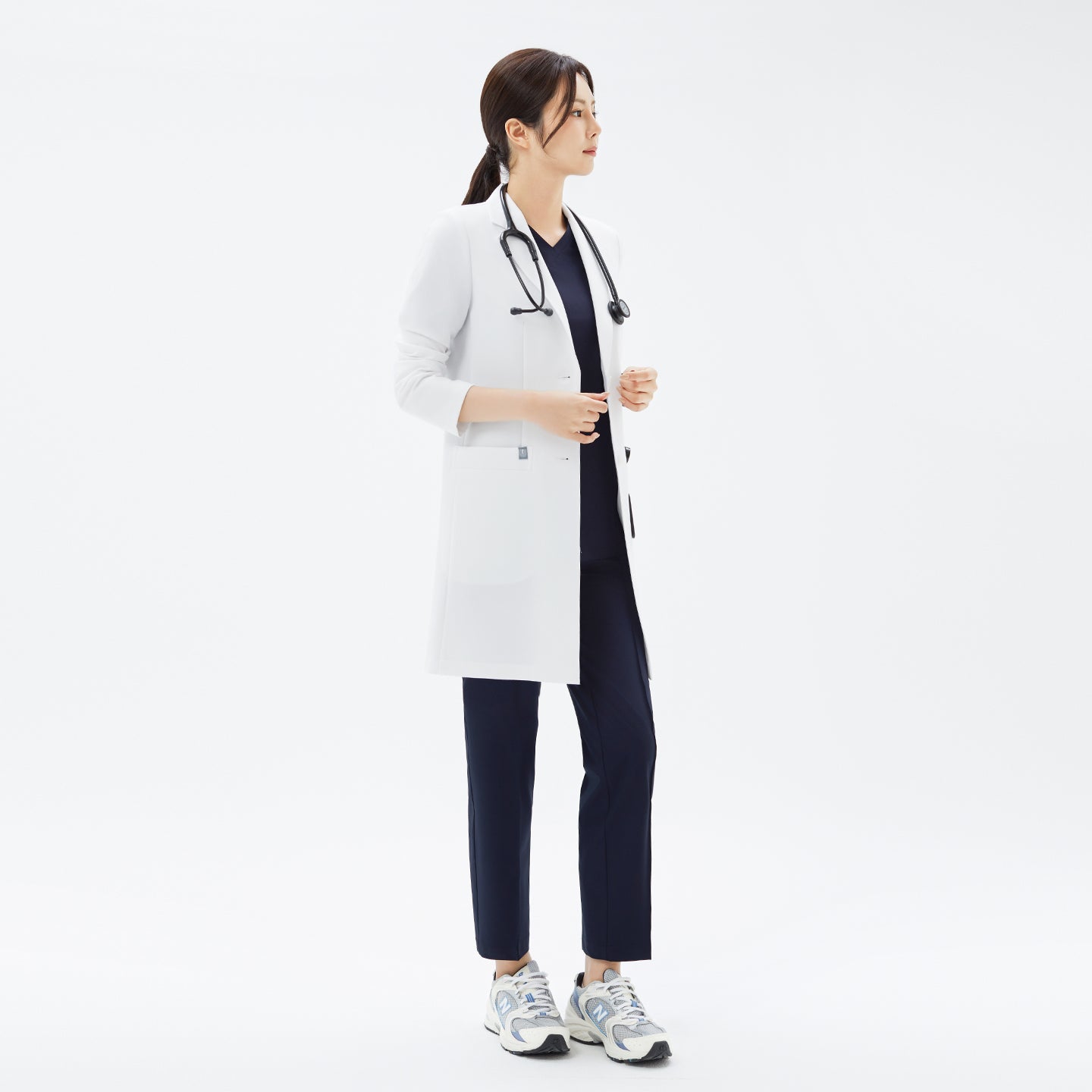 Image of Full body view of woman in sneakers wearing the TUL Women's LCW-18 Classic Long Lab Coat in White with stethoscope.