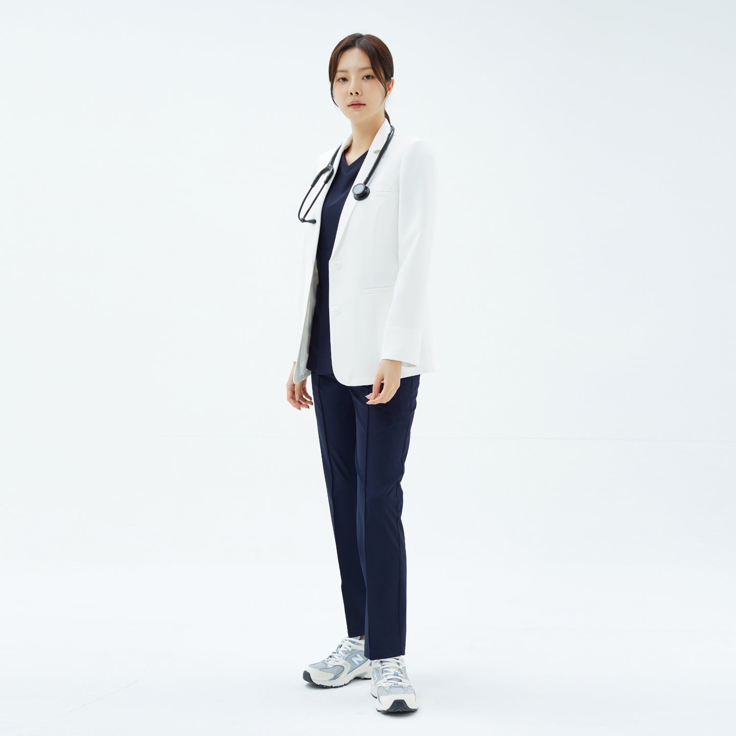 Image of Standing pose of the model wearing the TUL Women's LCW-20 Elite Short Lab Coat with medical accessories.