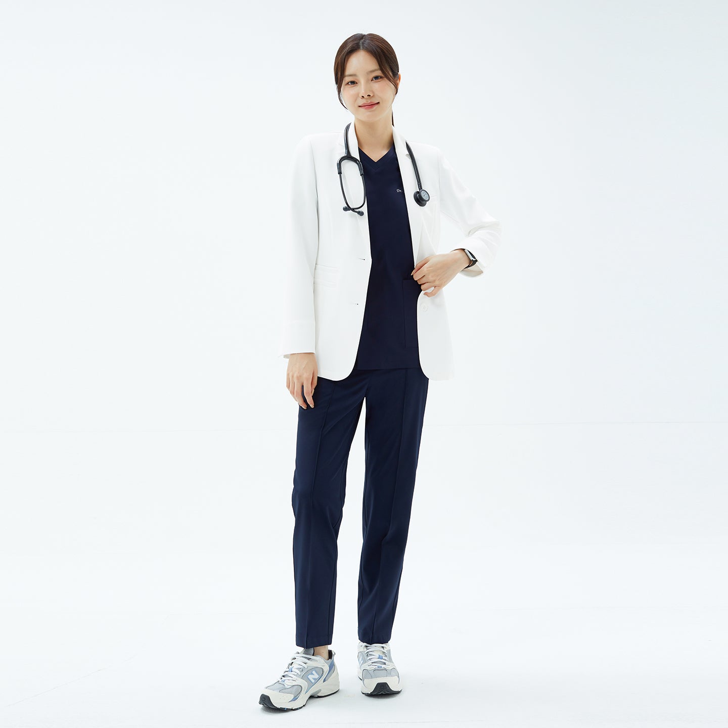 Image of Full body shot of the TUL Women's LCW-20 Elite Short Lab Coat styled with a stethoscope and navy scrubs.