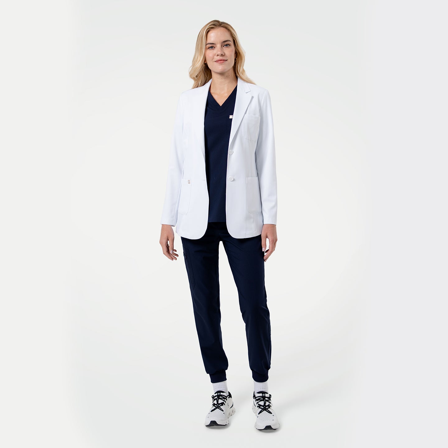 Image of Model wearing a white medical lab coat over navy scrubs, showcasing the professional fit on a light gray background.