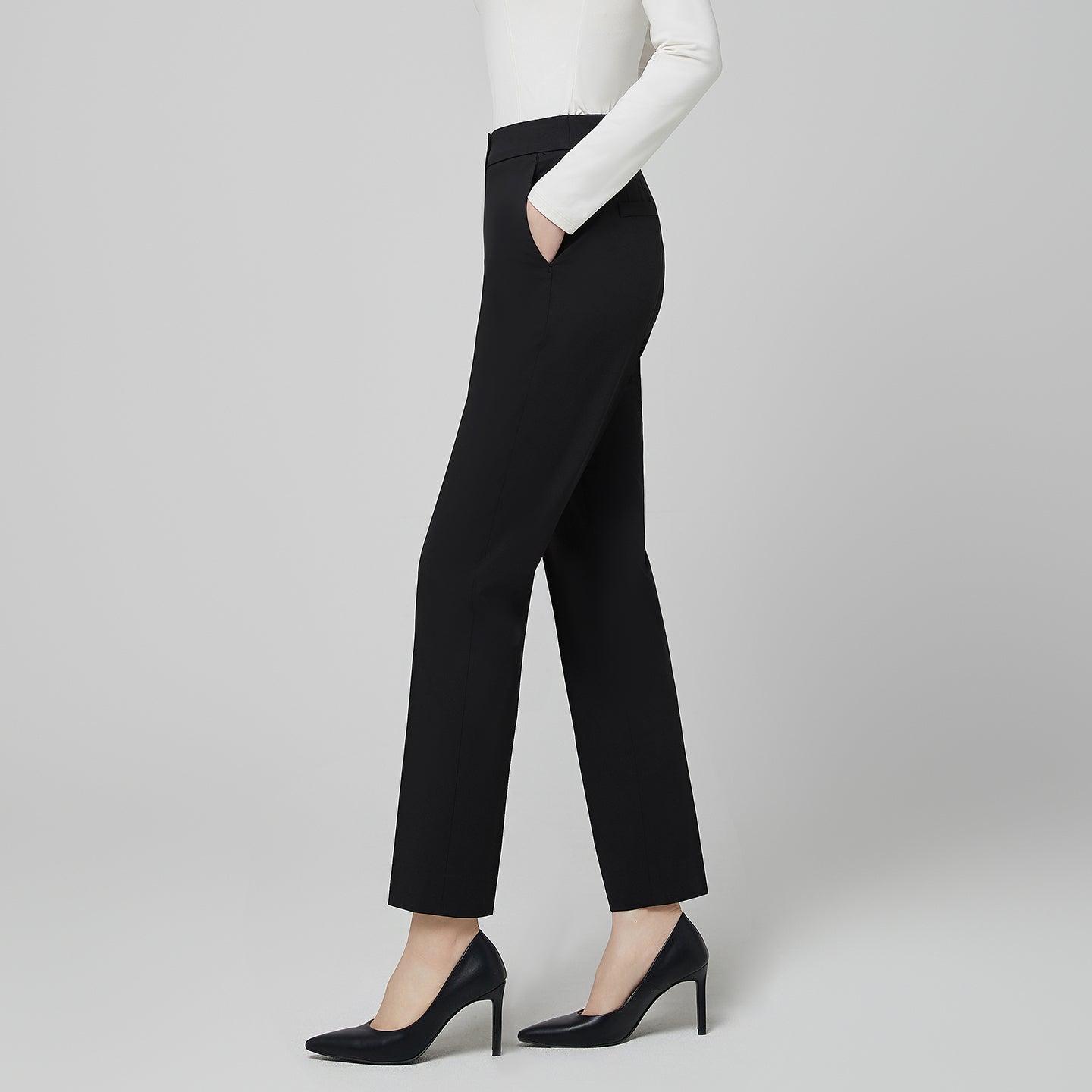 Lifestyle image of a model wearing TUL Women's CS Straight Banding Pants in YT Black in a clinical setting, demonstrating a versatile, professional look with a well-fitted, straight-leg cut and crisp banding detail.