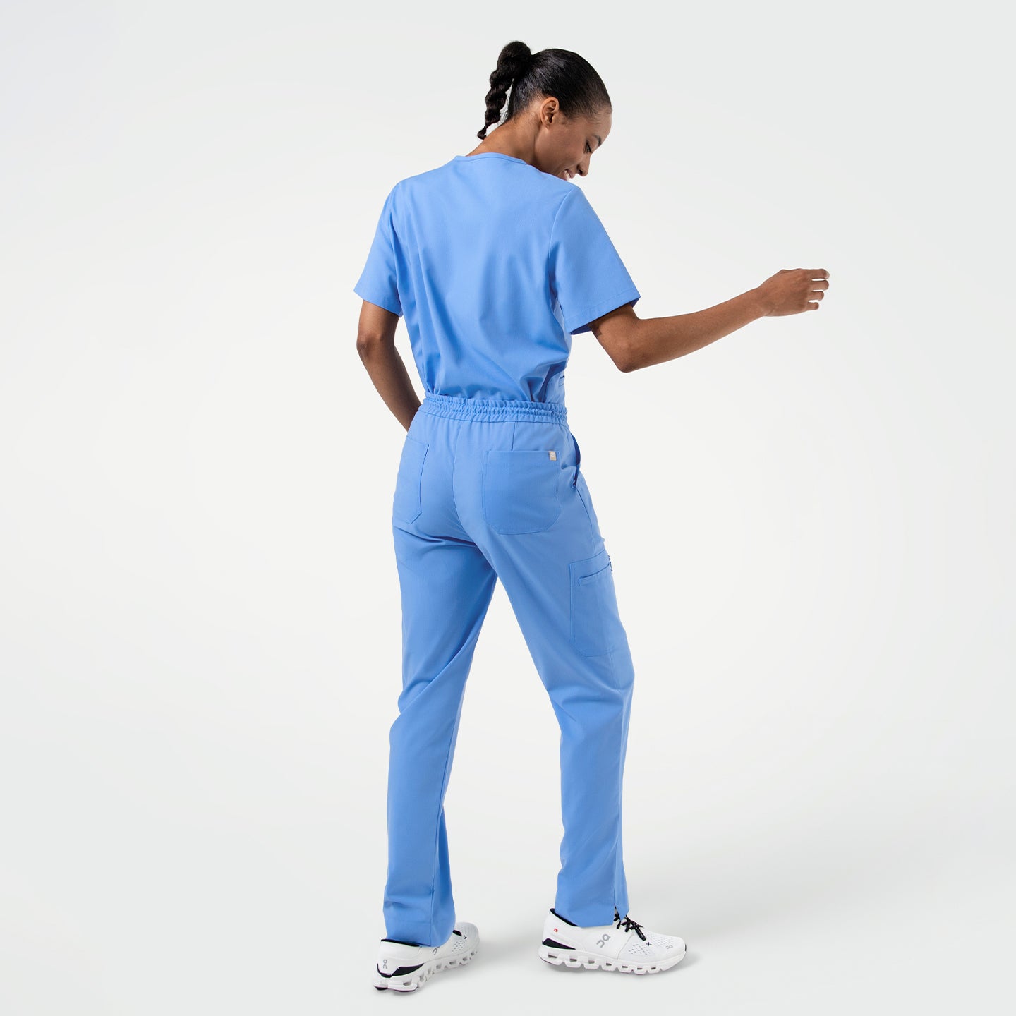 Image of Back angled view of Ceil Blue zipper pocket split hem scrub pants paired with a matching scrub top, showing elastic waistband, rear and side pockets, and straight leg cut with side slits.