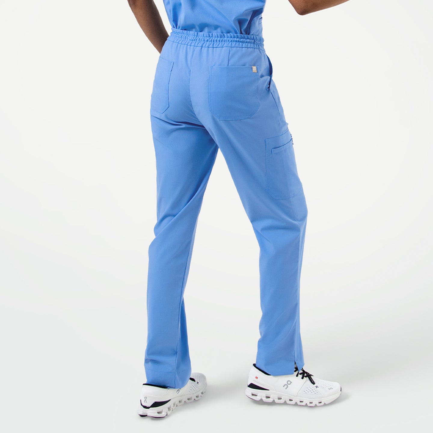 Image of Back view of Ceil Blue zipper pocket split hem scrub pants, showing elastic waistband, rear pockets, and straight leg design with side slit at the hem.